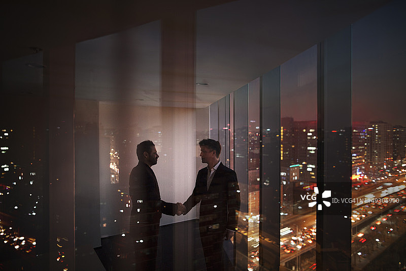 商人在夜晚的办公室里握手图片素材