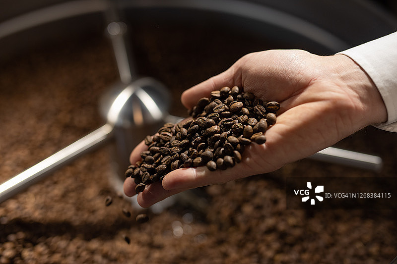 手持烘焙黑咖啡豆特写图片素材