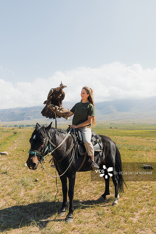 女旅行者在中亚山区手持金雕图片素材