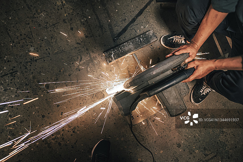 亚裔中年男子在车间焊接金属图片素材