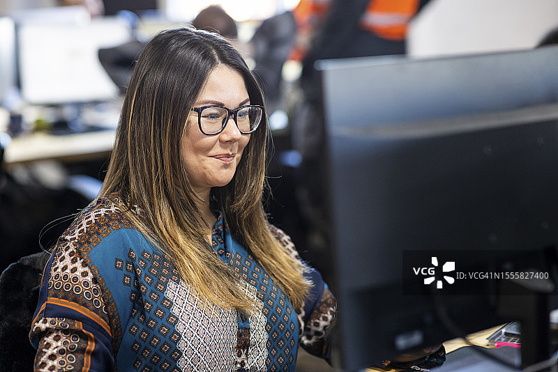 笑容满面的女商人戴着眼镜在办公室用电脑工作图片素材