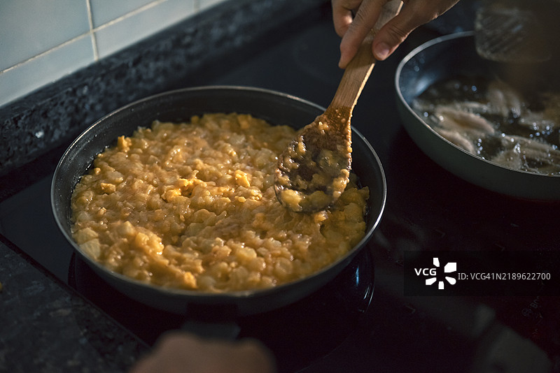 在家用平底锅制作土豆煎蛋饼并炸小鱼。图片素材