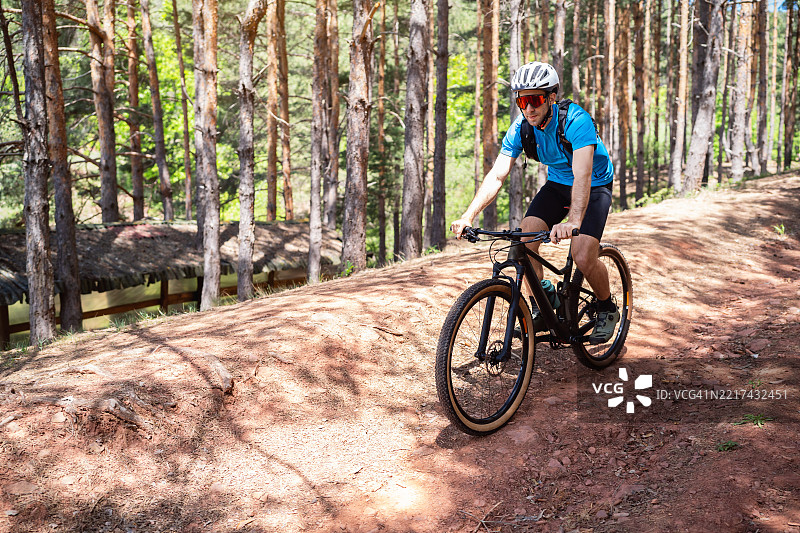 运动员在白天的风景如画的森林小径上享受山地自行车骑行图片素材