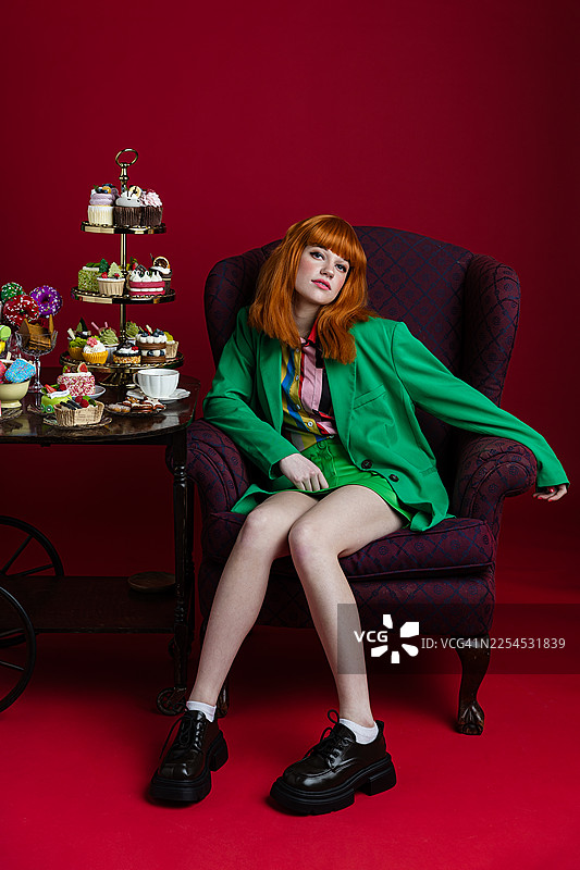 身着绿色套装的时尚女子与精心布置的甜点展示图片素材